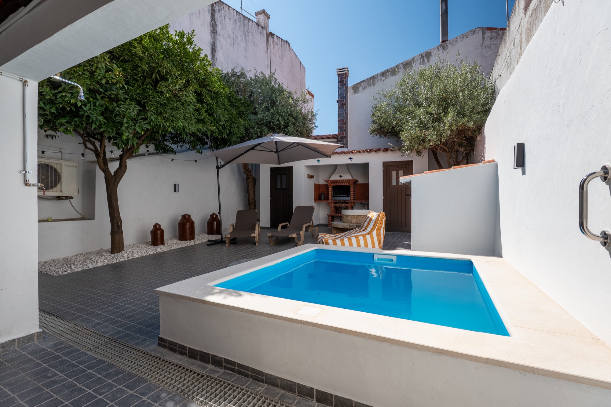 Pátio com piscina, laranjeira e chapéu-de-sol