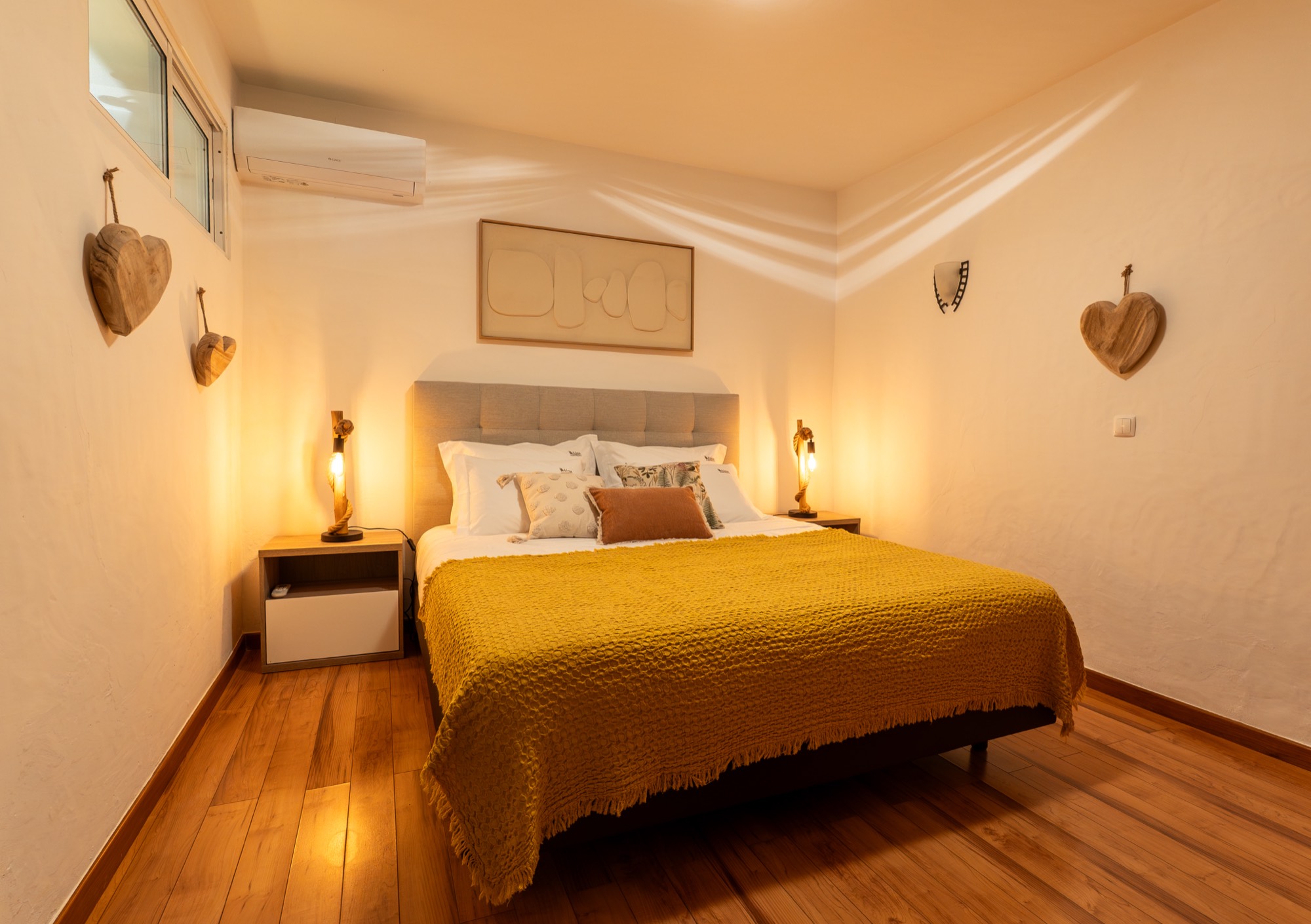 Quarto com cama king size, cómoda em madeira e corações decorativos na parede