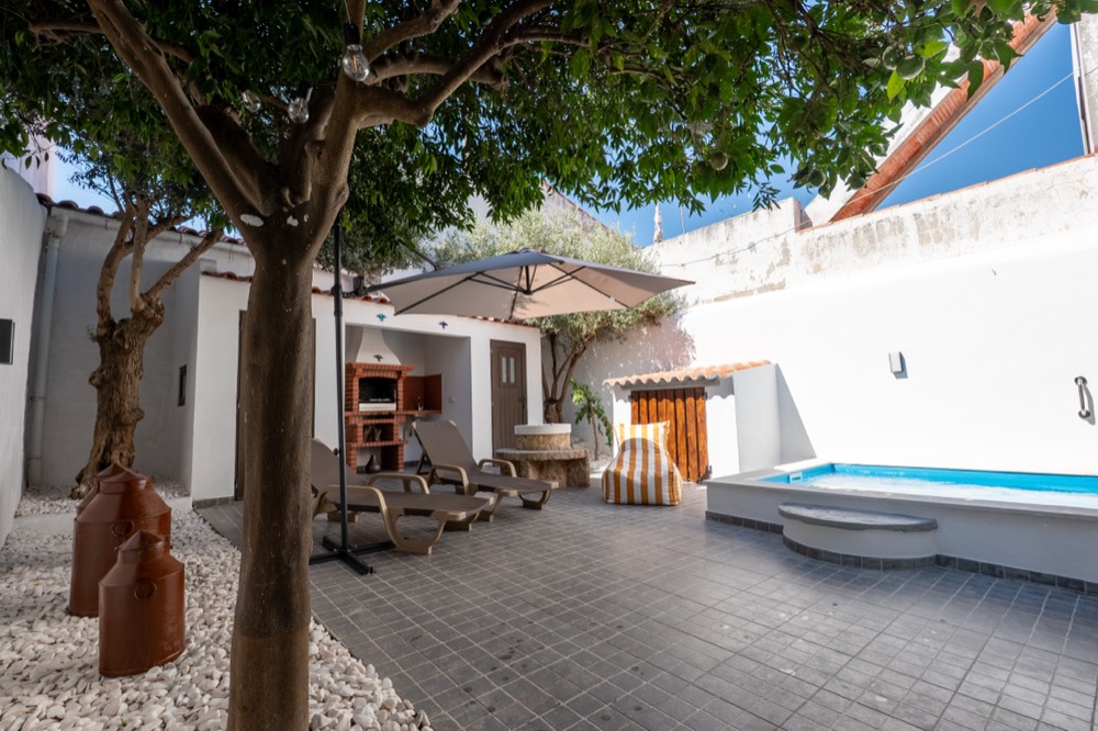 Pátio com árvore, espreguiçadeiras e pequena piscina