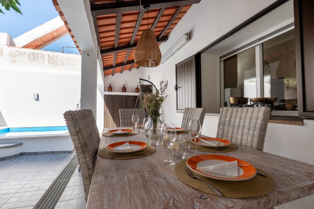 Mesa coberta no pátio com loiça e copos de vinho